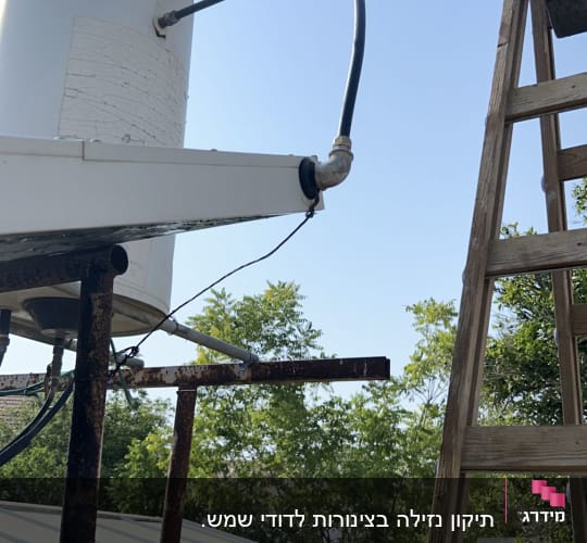 מיכל מים עם צינור וסולם לידו